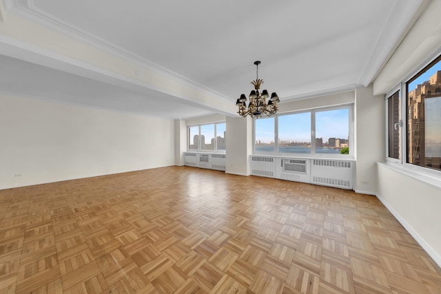 empty room featuring an inviting chandelier, radiator, crown molding, and baseboards