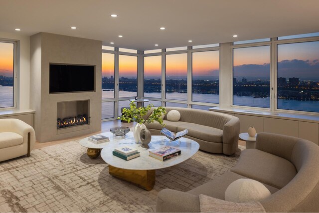 living area featuring a view of city, a fireplace, recessed lighting, a water view, and a wall of windows