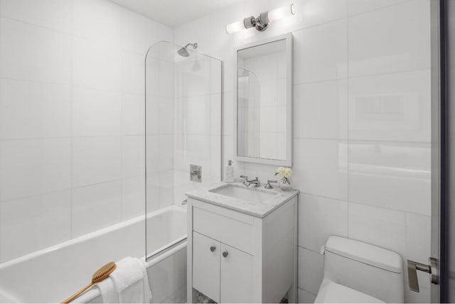 bathroom featuring toilet, washtub / shower combination, tile walls, and vanity