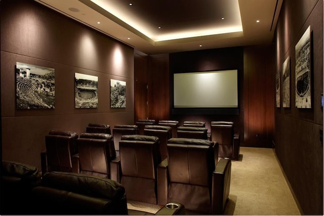 home theater room with light carpet, wooden walls, and a tray ceiling