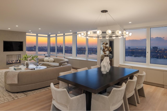 dining space with a view of city, a multi sided fireplace, light wood-style flooring, and recessed lighting