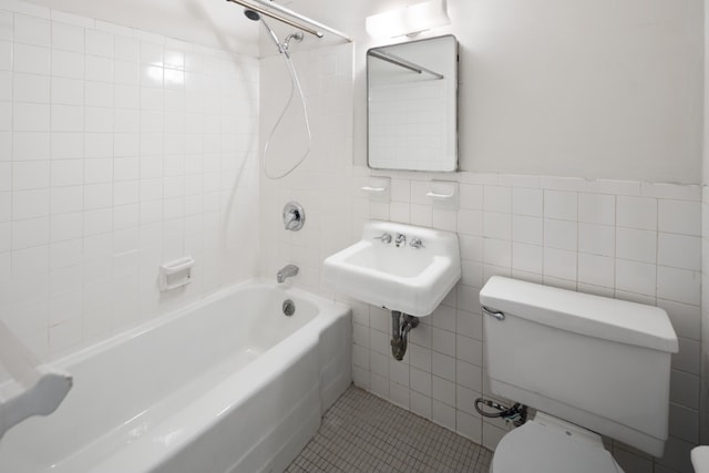 bathroom featuring tile patterned floors, toilet, a sink, tile walls, and  shower combination