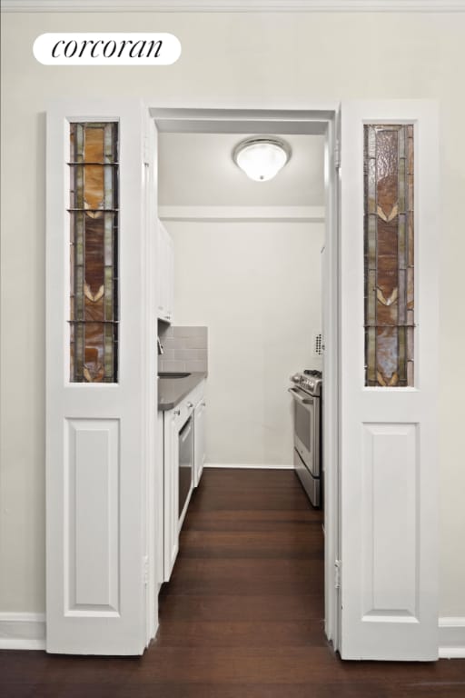 kitchen with dark wood-type flooring, white cabinetry, stainless steel gas stove, decorative backsplash, and sink