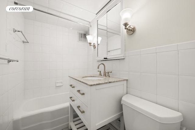 full bathroom featuring toilet, tile walls, tiled shower / bath, and vanity