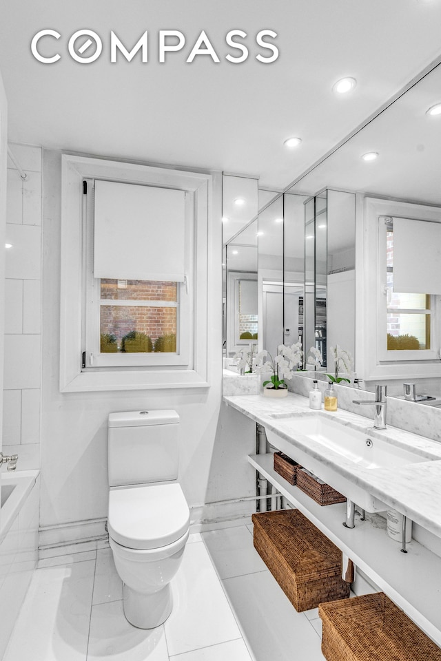 full bathroom with a bathtub, recessed lighting, toilet, a sink, and baseboards