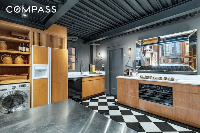 interior space with dark floors, a sink, light countertops, black appliances, and washer / dryer