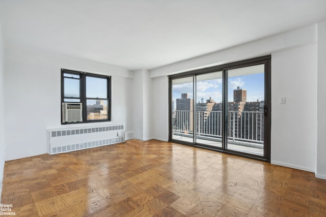 unfurnished room with radiator, a view of city, baseboards, and cooling unit