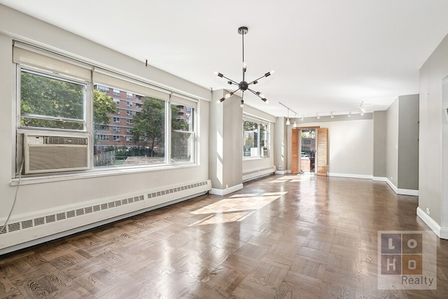 unfurnished living room with cooling unit, an inviting chandelier, track lighting, parquet floors, and a baseboard radiator