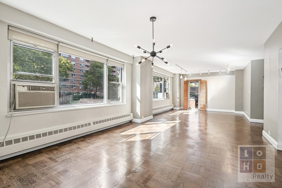 empty room featuring cooling unit, baseboards, a baseboard radiator, rail lighting, and a notable chandelier