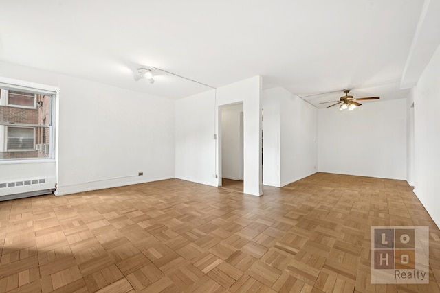 empty room featuring a ceiling fan and radiator