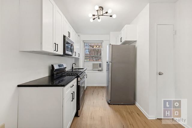 kitchen with baseboards, white cabinets, appliances with stainless steel finishes, light wood-type flooring, and a chandelier