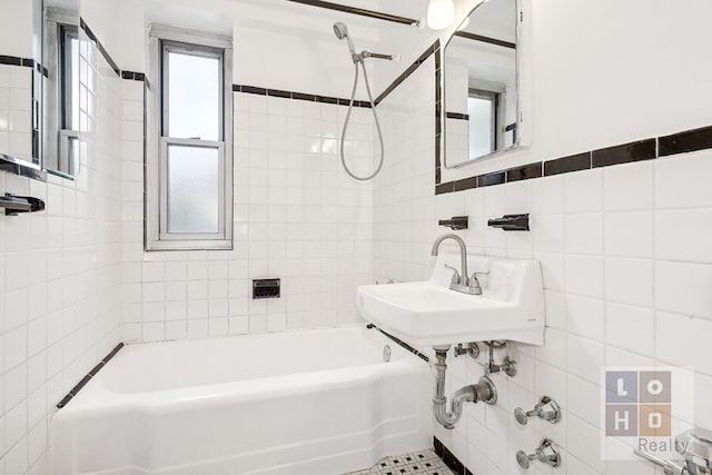 full bathroom featuring washtub / shower combination, a sink, and tile walls