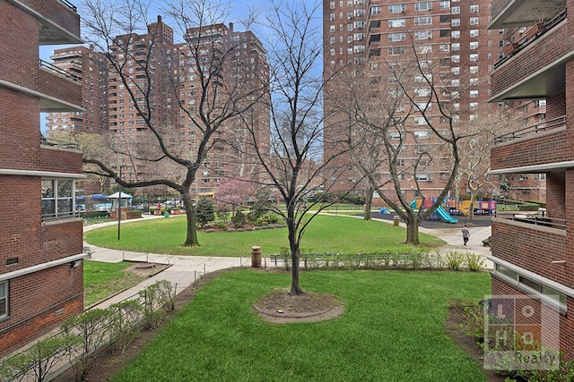 view of property's community with playground community and a yard