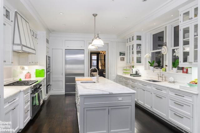 kitchen featuring white cabinetry, sink, an island with sink, and custom range hood