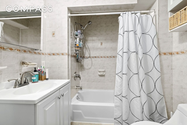 bathroom featuring tasteful backsplash, toilet, shower / tub combo with curtain, vanity, and tile walls