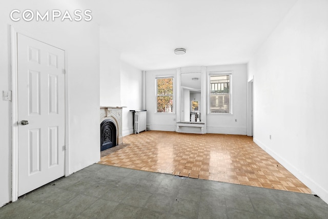 unfurnished living room featuring radiator, a fireplace, and baseboards