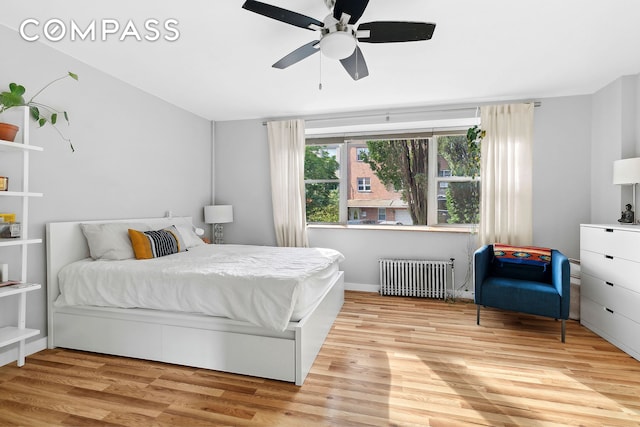 bedroom featuring ceiling fan, light wood-style floors, and radiator