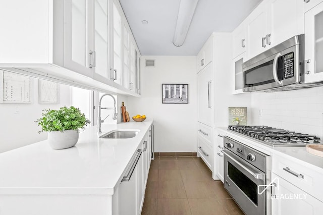 kitchen featuring backsplash, sink, white cabinetry, stainless steel appliances, and light tile patterned floors