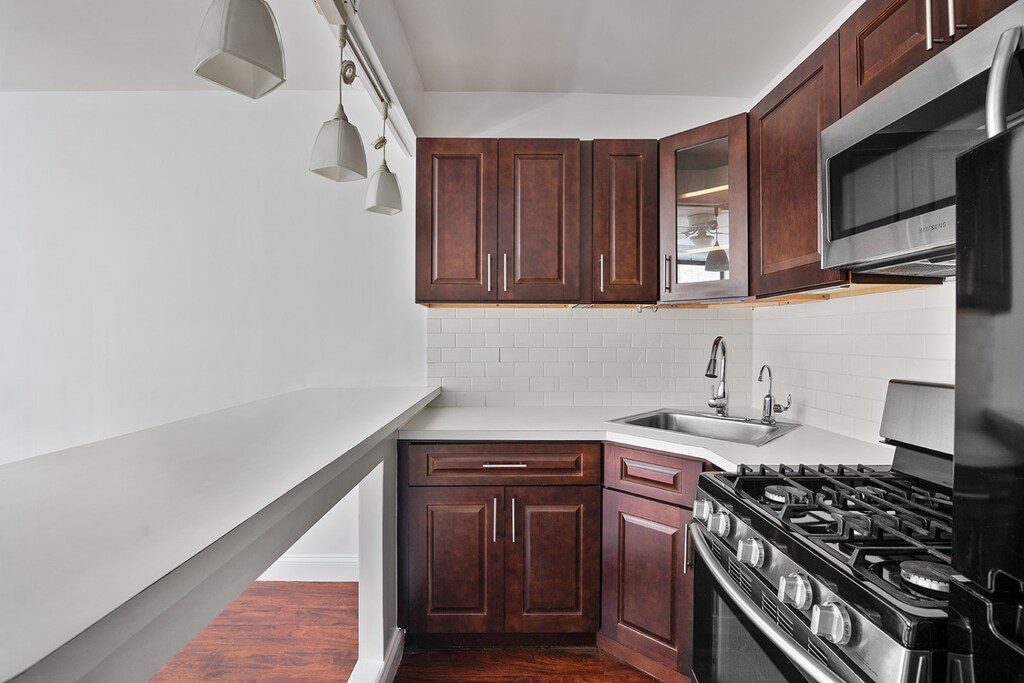 kitchen featuring stainless steel appliances, sink, dark wood-type flooring, and backsplash