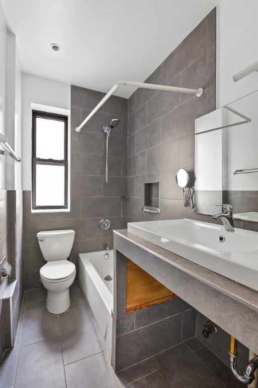 bathroom featuring tile patterned floors, toilet, tiled shower / bath combo, and tile walls