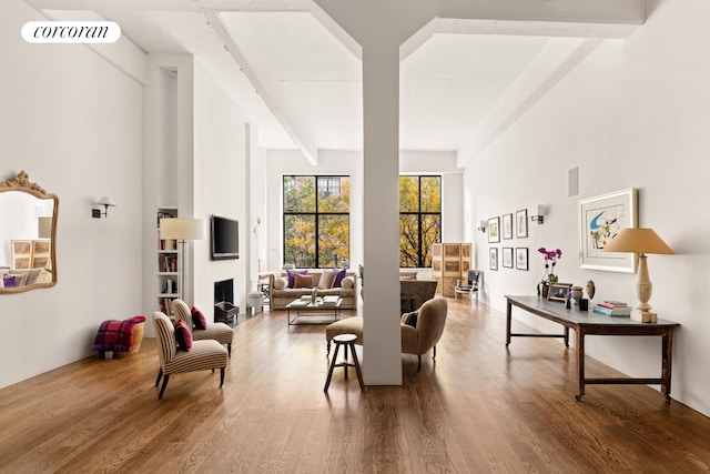 living room featuring beamed ceiling, wood finished floors, and visible vents