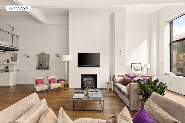 living room featuring beamed ceiling, a fireplace, wood finished floors, and visible vents