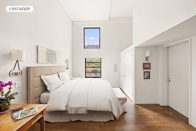 bedroom with a high ceiling, visible vents, and wood finished floors