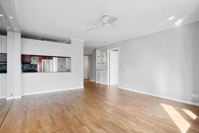 unfurnished living room with sink, ceiling fan, and light wood-type flooring