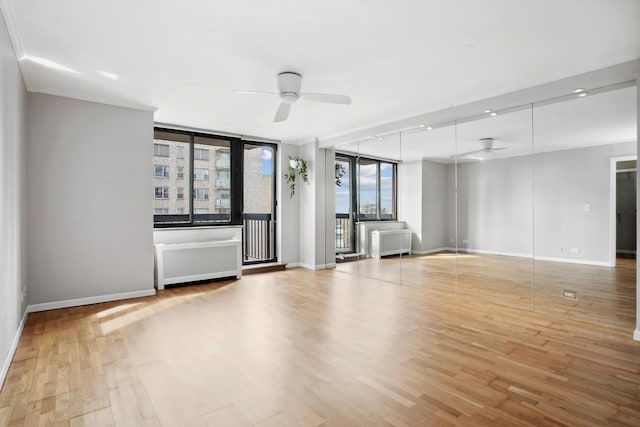 empty room featuring a ceiling fan, wood finished floors, baseboards, and ornamental molding