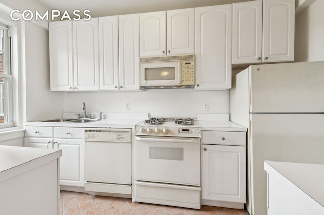 kitchen with light countertops, white appliances, a sink, and white cabinetry