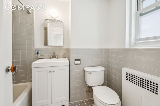 full bathroom with radiator, a wainscoted wall, toilet, vanity, and tile walls