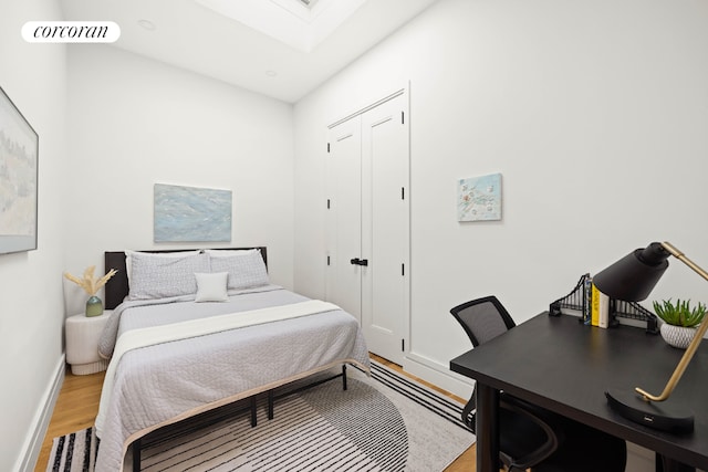 bedroom with light wood-style flooring, a skylight, visible vents, baseboards, and a closet