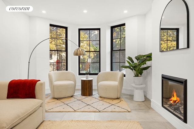 living area featuring plenty of natural light, a glass covered fireplace, visible vents, and recessed lighting