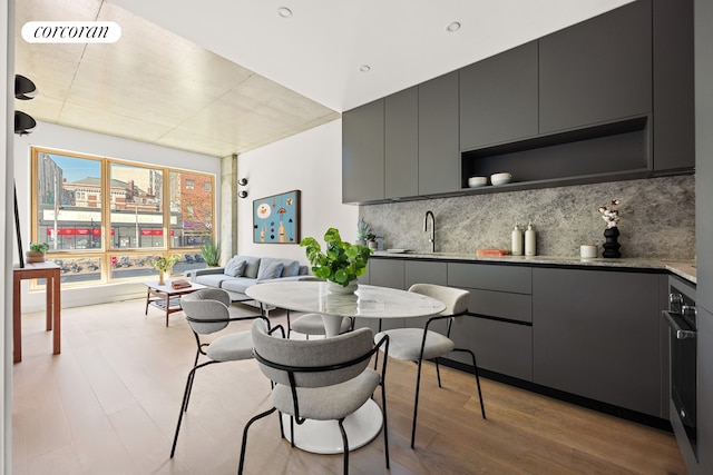 1118 Fulton St Unit 2R, New York City, NY 11238 - kitchen featuring gray cabinets, tasteful backsplash, light wood-type flooring, open shelves, and stainless steel oven