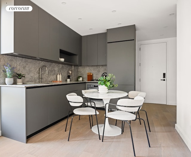 kitchen featuring backsplash, modern cabinets, light wood-style flooring, and gray cabinets