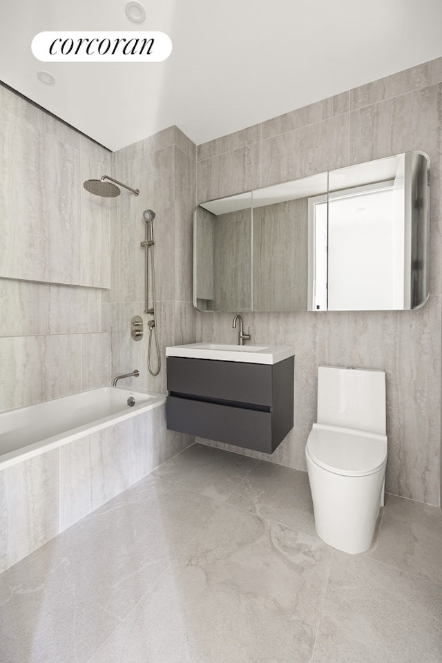 bathroom with toilet, tile walls, vanity, and tiled shower / bath combo