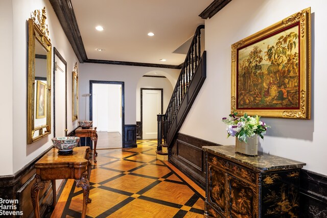 foyer entrance featuring crown molding, a wainscoted wall, stairs, recessed lighting, and arched walkways