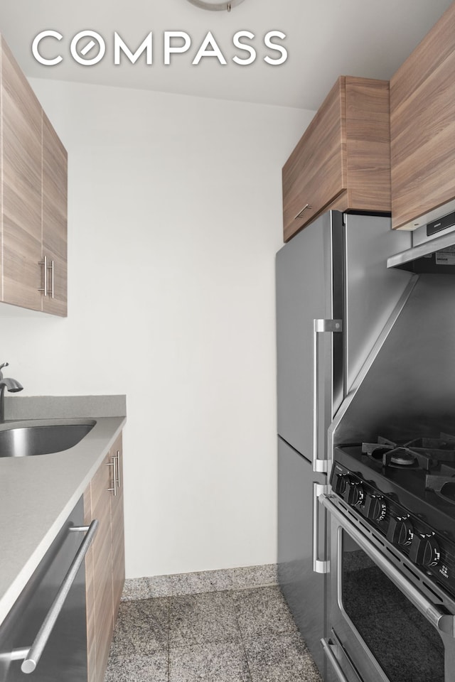 kitchen with brown cabinetry, modern cabinets, appliances with stainless steel finishes, light countertops, and a sink