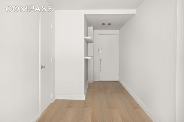 hall featuring light wood finished floors and baseboards