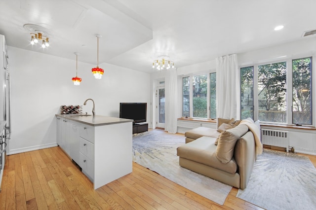 living room featuring radiator, sink, and light hardwood / wood-style floors