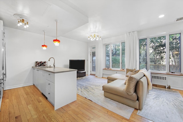 living room with visible vents, baseboards, radiator heating unit, recessed lighting, and light wood-style flooring