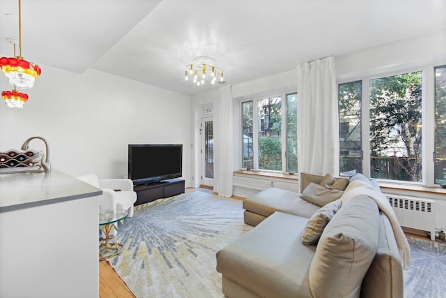 living room with radiator, light hardwood / wood-style flooring, and a chandelier