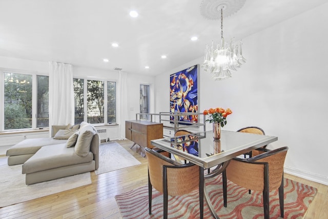 dining area with a chandelier, radiator, and light hardwood / wood-style flooring