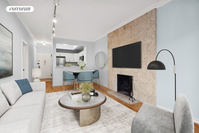 living room featuring crown molding, hardwood / wood-style floors, and a tile fireplace