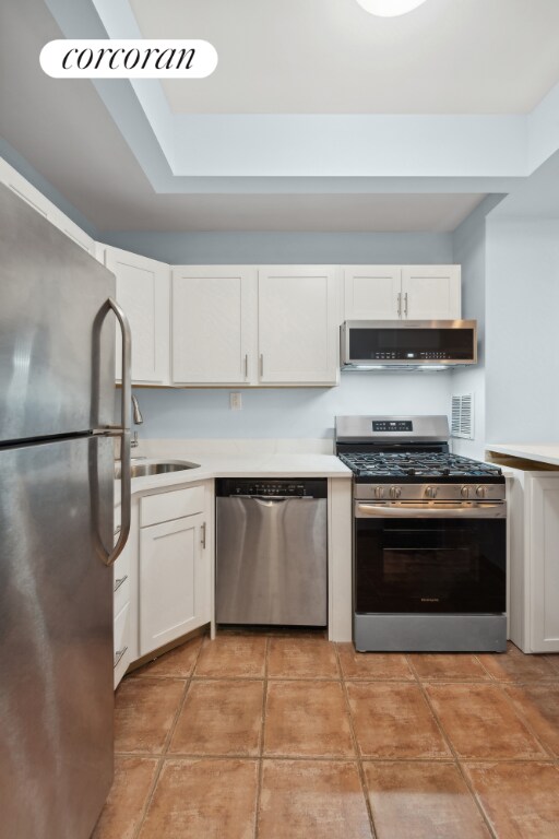 kitchen featuring white cabinetry, appliances with stainless steel finishes, extractor fan, and light tile patterned floors