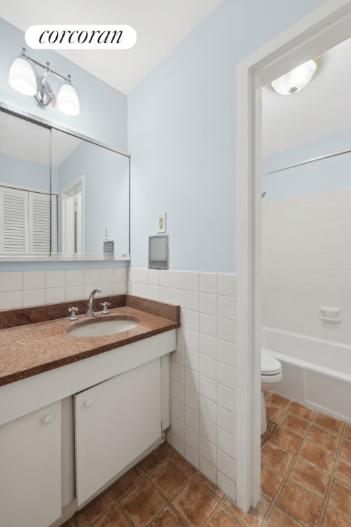 full bathroom featuring toilet, vanity, tile walls, and shower / bathing tub combination