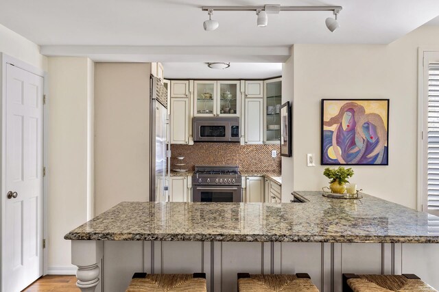 339 E 58th St Unit 7Cd, New York City, NY 10022 - kitchen with premium appliances, a peninsula, light stone countertops, and a breakfast bar