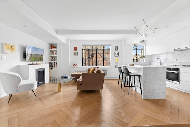 living room with light parquet flooring, built in features, and sink