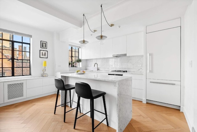 kitchen with light parquet flooring, backsplash, white cabinets, and paneled fridge