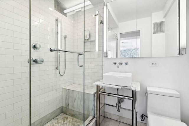 bathroom with sink, toilet, and a shower with door